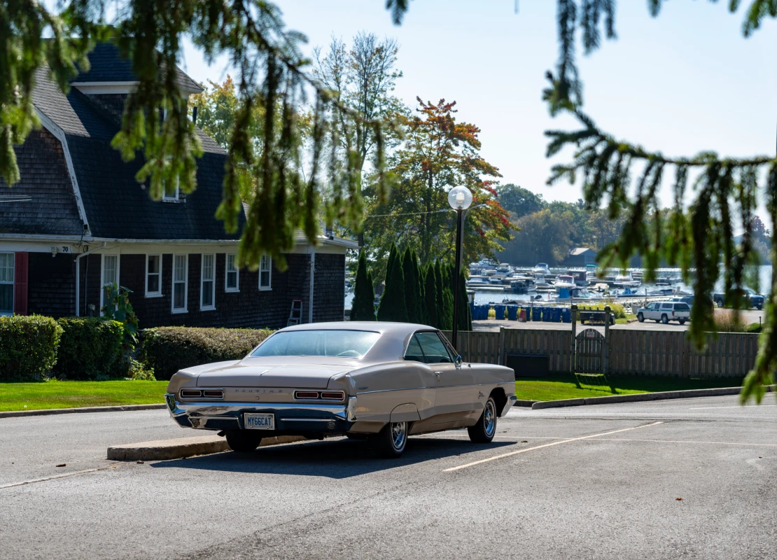 Gananoque on Lake Ontario, a port for The Thousand Islands boat tours. A classic American car, 1966 Pontiac Catalina, in a car park near the tour boat pier.