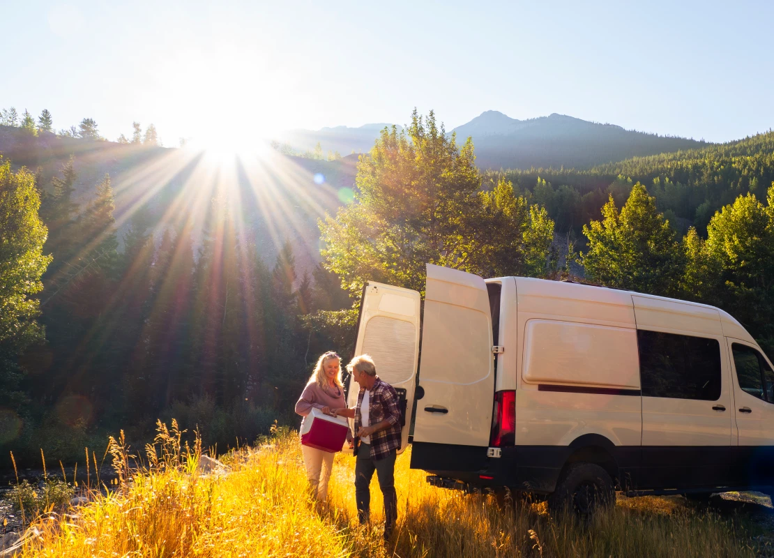 Mature couple leave camper van with picnic cooler